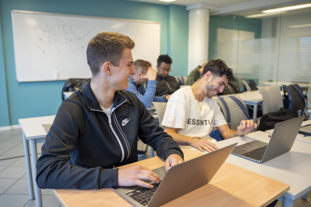 Elever ler ved laptop med tavle i bakgrunnen hvor det står Helen er best